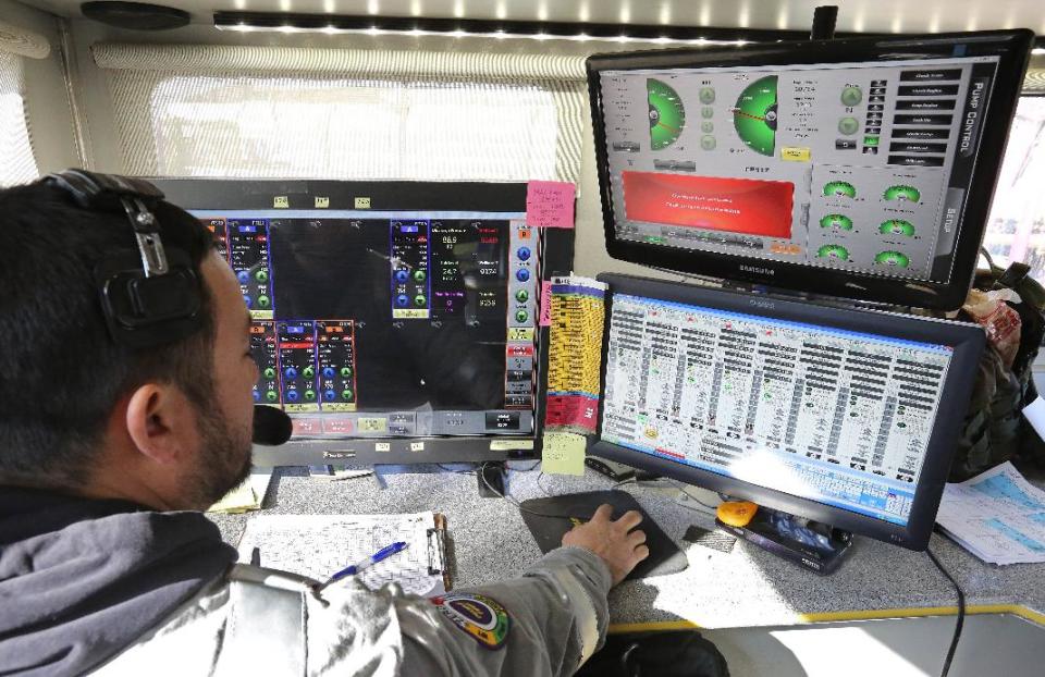 In this March 25, 2014 photo, a technician inside a trailer monitors and directs the pressure and mix of water, sand and chemicals pumped during a hydraulic fracturing operation at an Encana Corp. well pad near Mead, Colo. It takes a few weeks for the half dozen wells on a typical pad to be fracked, after which the petroleum products are extracted for years by operators like Encana. (AP Photo/Brennan Linsley)