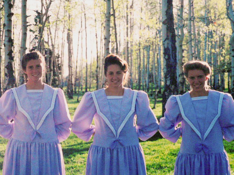 Four young women wearing Prairie dresses are shown standing in line when they were members of the Fundamental Church of the Latter-Day Saints.