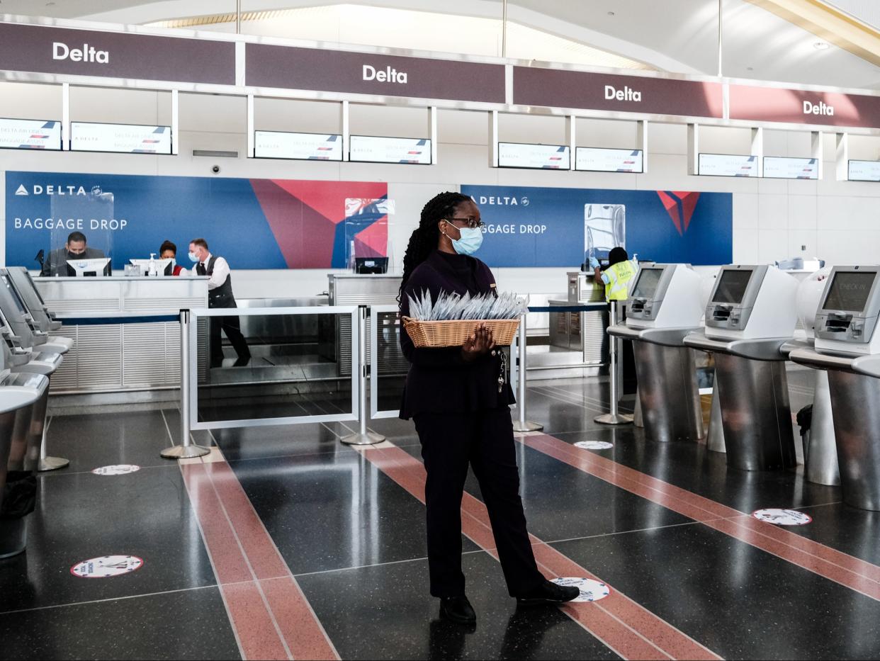 A Delta Airline employee hands out face masks to passengers during check in at the Ronald Reagan National Airport on 22 July 2020 in Arlington, Virginia ((Getty Images))