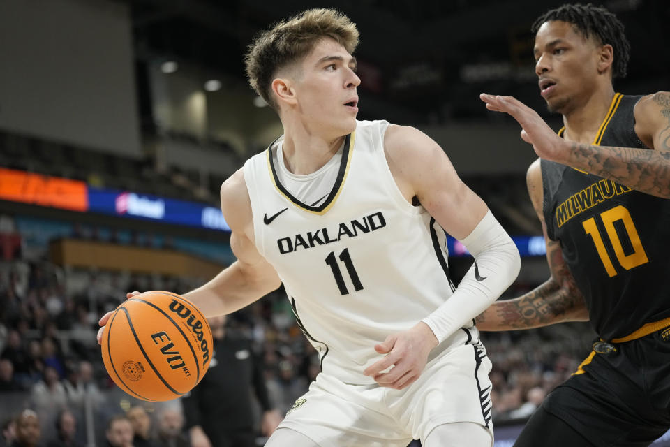 Oakland guard Blake Lampman (11) looks to pass around Milwaukee guard BJ Freeman (10) during the first half of an NCAA college basketball game for the championship of the Horizon League men's tournament in Indianapolis, Tuesday, March 12, 2024. (AP Photo/AJ Mast)