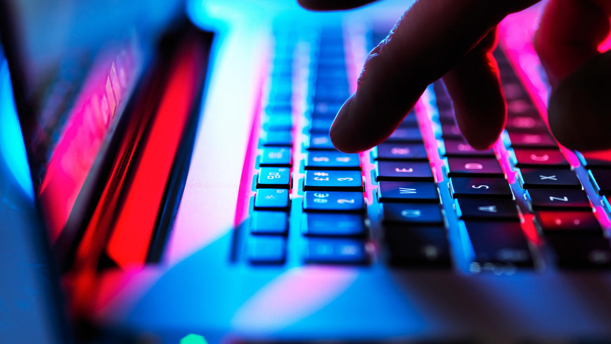  Man typing at his laptop computer at night. 