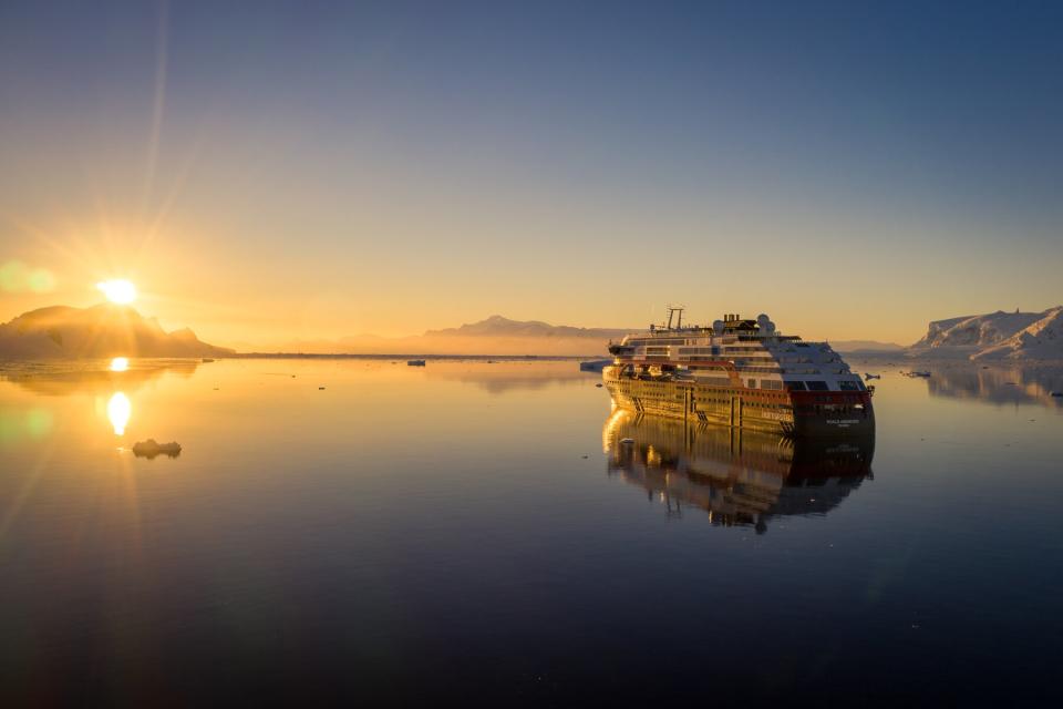 Small cruise ship on glass smooth water looking at the sun