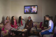 Family members, from right to left, Suhail Lahta, Ghita Naoui, Fadila Lahta, Zineb Jammar, and Fatima Naoui drink tea and watch TV as they spend the first day of Eid in lockdown due to the Coronavirus pandemic, in Sale, Morocco, Sunday, May 24, 2020. (AP Photo/Mosa'ab Elshamy)