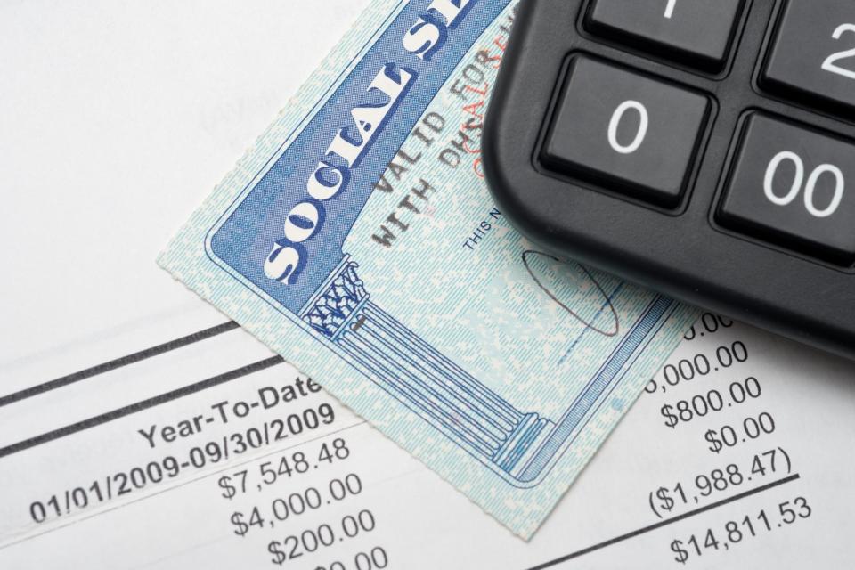 A Social Security card under a calculator and on top of a financial statement.