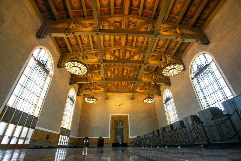 A view upward of an ornate ceiling, lights, and floor-to-ceiling windows.