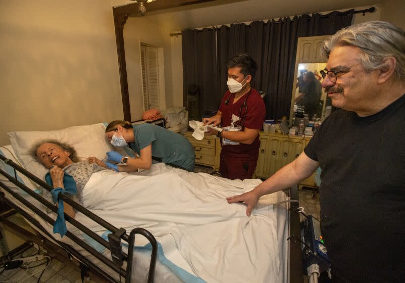 LOS ANGELES, CA-OCTOBER 7, 2022: Licensed Vocational Nurse Angela Tapia administers a dose of the Moderna COVID-19 booster vaccine to Maria Salazar, 88, at her home in Los Angeles as her son Louis Salazar Jr. 64, right, and Public Health Nurse Bryan Phan observe. Louis and his father Louis Sr. 90, were earlier given the booster shot by Tapia. The Los Angeles County Department of Public Health runs a program that provide COVID vaccines to people who are homebound. (Mel Melcon / Los Angeles Times)