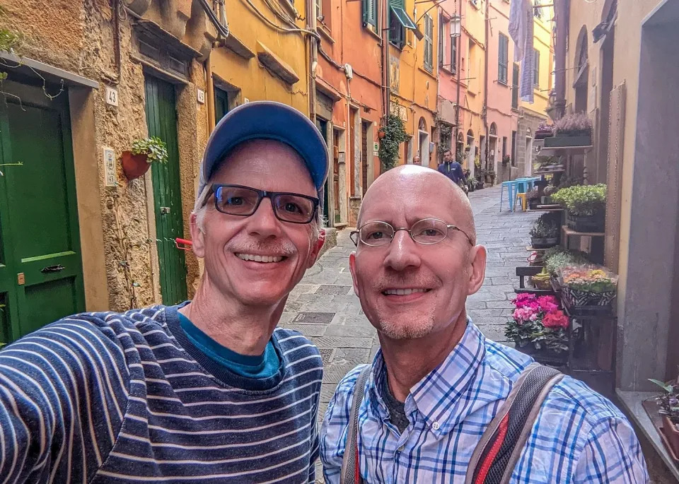 Brent and Michael standing in the center of town, the cobblestone street stretching back between colorful buildings