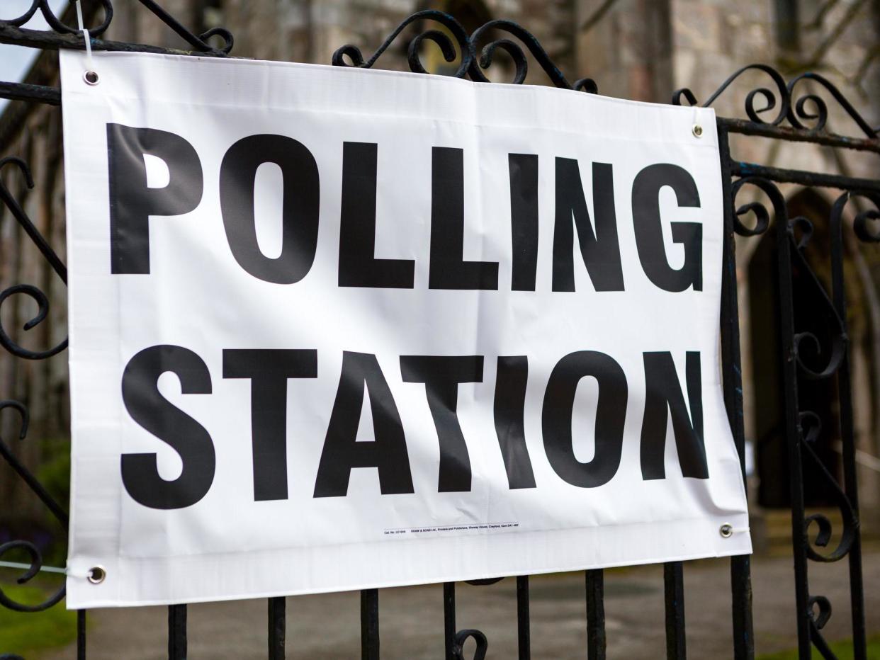 A vinyl polling station banner tied to railings with a church door visible in the background: Getty Images