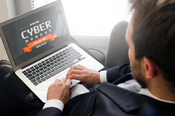 A man sits at a laptop with an illustration that says Cyber Monday.