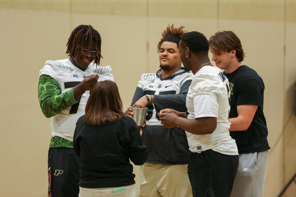 Purdue Boilermaker football freshman offensive lineman André Oben, offensive lineman Malachi Preciado, defensive end Nic Caraway and Purdue student Andrew Buban pull names out of a tin cup to give students a signed book, during Edgelea Elementary School's ILEARN prep rally, on Friday, April 7, 2023, in Lafayette, Ind.