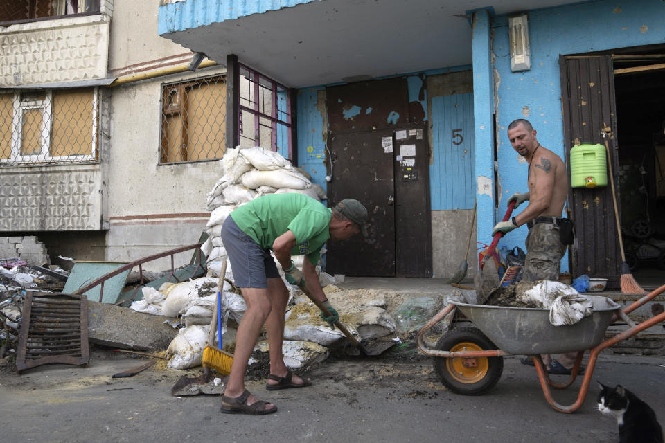 ARCHIVO - Viktor Lazar, a la derecha, limpia la calle ante su apartamento en el distrito de Saltivka tras ataques rusos en Járkiv, Ucrania, el 5 de julio de 2022. (AP Foto/Evgeniy Maloletka, Archivo)