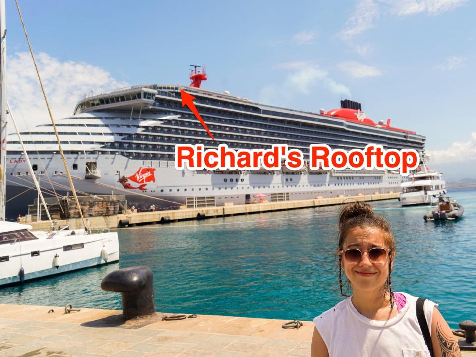 The author on the right in front of a docked cruise ship with the water and blue skies behind her. There's a red arrow on the ship pointing to Richard's Rooftop