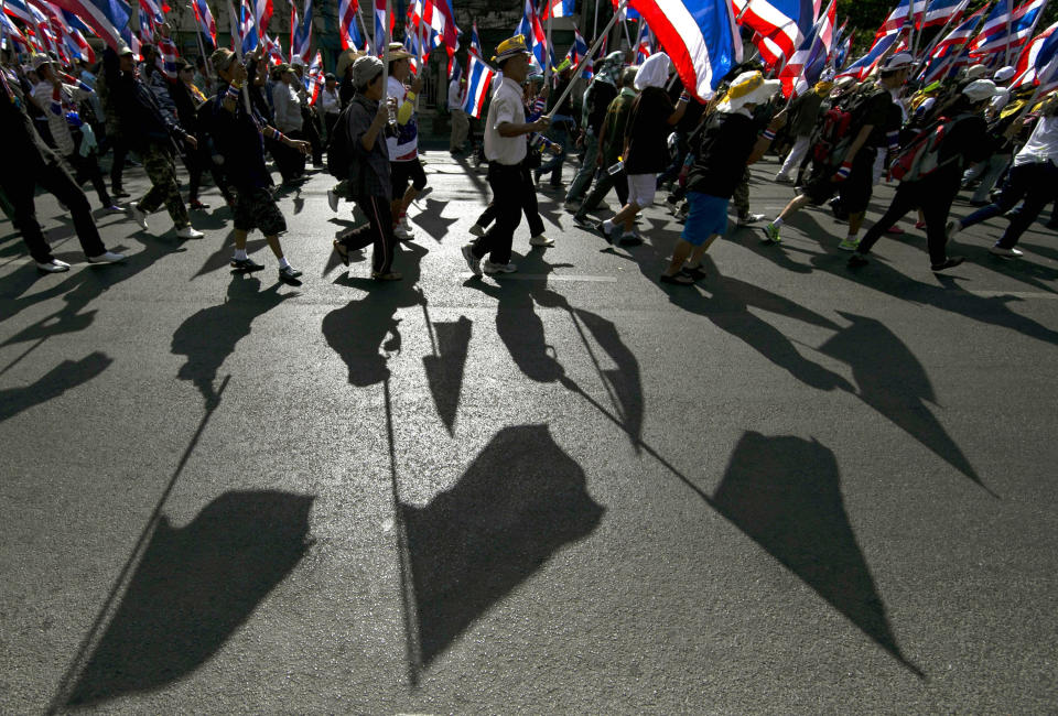 Thai anti-government protesters march with national flags as they head to the office of the National Economic and Social Development Board (NESDB) Tuesday, Jan. 14, 2014, in Bangkok, Thailand. Anti-government protesters who blocked off intersections across Thailand's capital began marching toward several government ministries Tuesday on the second day of a renewed push to derail elections next month and unseat the prime minister. (AP Photo/Wason Wanichakorn)