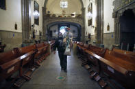 A devotee, wearing a protective face mask amid the new coronavirus pandemic, carries his Saint Jude statue into the San Hipolito Catholic church, during the annual pilgrimage honoring Jude, the patron saint of lost causes, in Mexico City, Wednesday, Oct. 28, 2020. Thousands of Mexicans did not miss this year to mark St. Jude's feast day, but the pandemic caused Masses to be canceled and the rivers of people of other years were replaced by orderly lines of masked worshipers waiting their turn for a blessing. (AP Photo/Marco Ugarte)