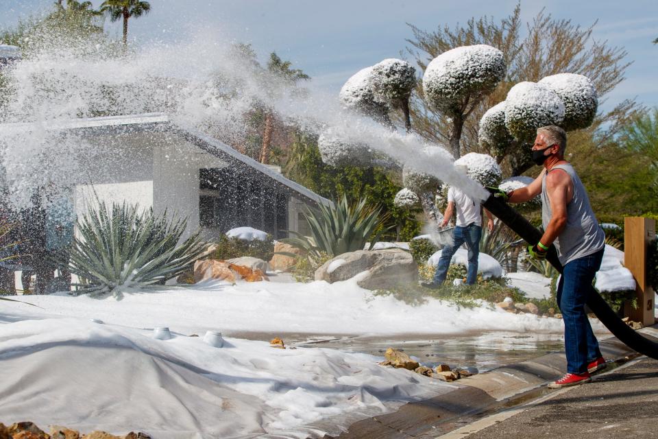 Freddie Rymond, manager of Long Beach Ice Co., sprays snow on the driveway of a home in the Old Las Palmas neighborhood in Palm Springs, Calif., on Wednesday, October 6, 2021. The real ice and some flocking on trees were being used for a commercial shoot.