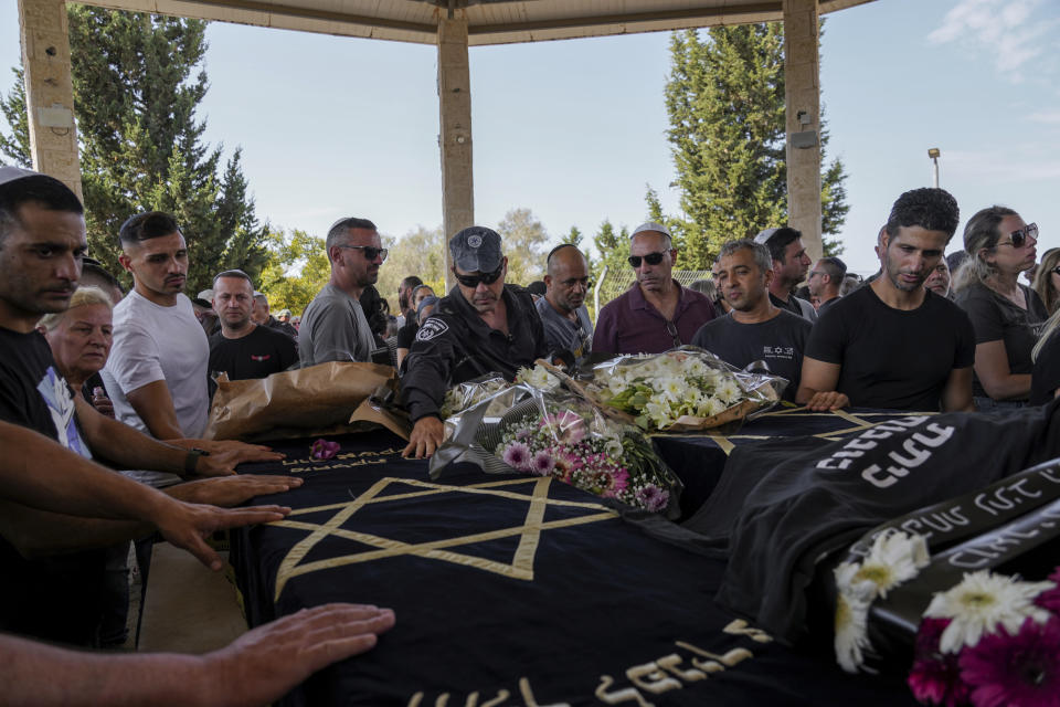 Mourners gather around the coffins of Gil Taasa and his son Or, during their funeral in Kibbutz Nitzan, Israel, Wednesday, Oct. 18, 2023. The Father and his son were killed by Hamas militants on Oct. 7 in Netiv Haasara, close to the Gaza Strip's separation fence with Israel, as the militant Hamas rulers of the territory carried out an unprecedented, multi-front attack that killed over 1,400 and captured many Israelis. (AP Photo/Tsafrir Abayov)