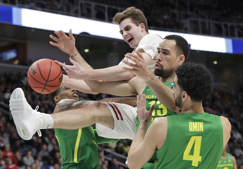 Wisconsin forward Nate Reuvers, top, reaches for a rebound over Oregon forward Paul White, second from right, and guard Ehab Amin (4) during the second half a first-round game in the NCAA men’s college basketball tournament, Friday, March 22, 2019, in San Jose, Calif. (AP Photo/Chris Carlson)