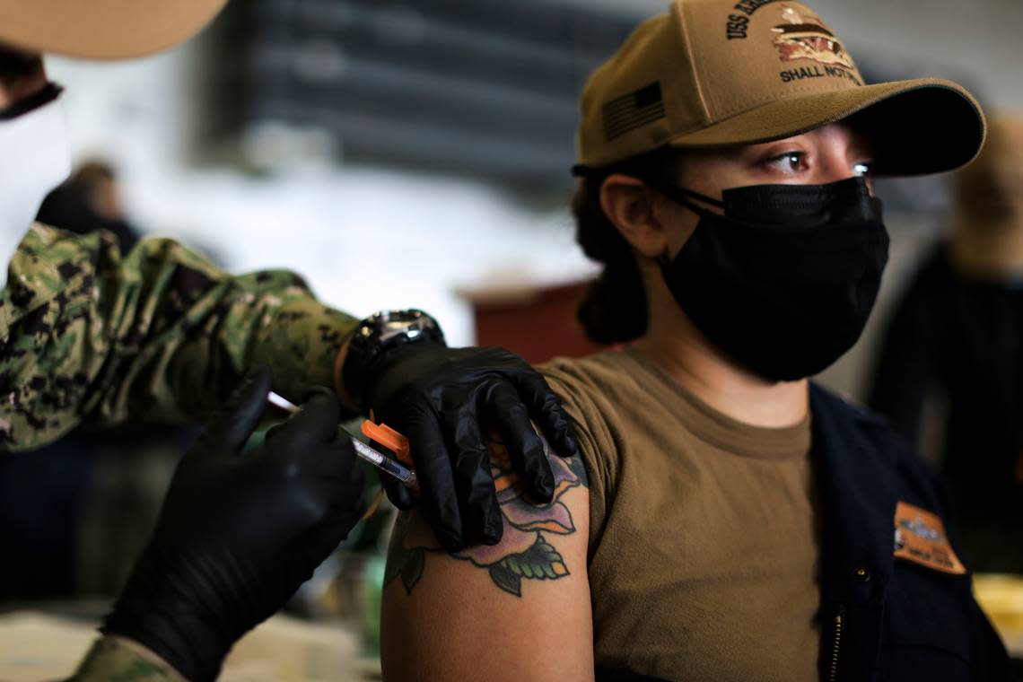 Machinist’s Mate (Nuclear) 1st Class Kayla Matos receives a COVID-19 booster shot during a shot event in the hangar bay aboard USS Abraham Lincoln on Dec. 28, 2021, in San Diego. All active-duty military personnel are required to be vaccinated against the coronavirus. (Petty Officer 3rd Class Lake Fultz/U.S. Navy/TNS)