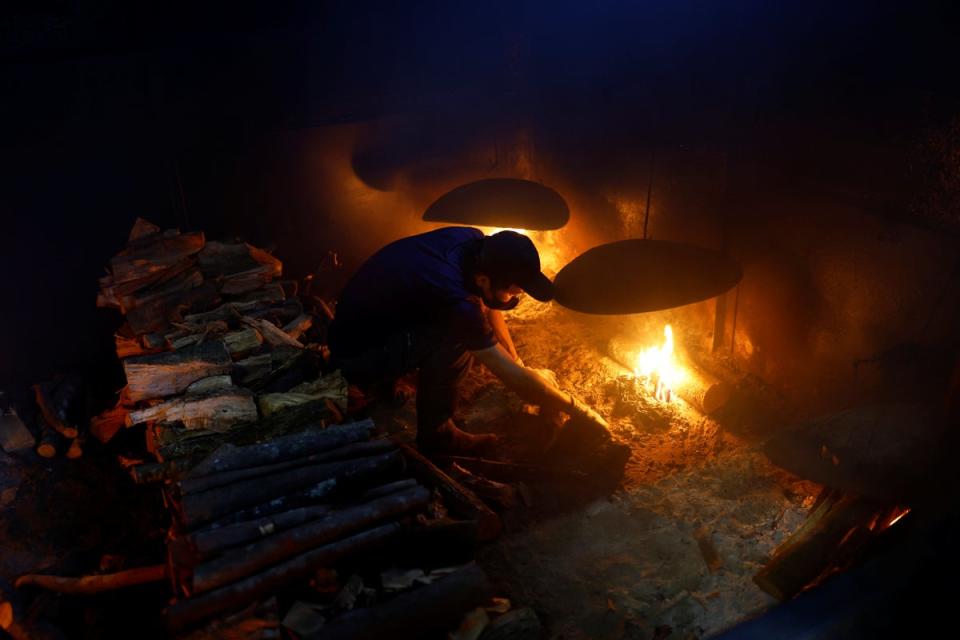 A worker uses firewood in a furnace to smoke the boiled fillets in the factory (Reuters)