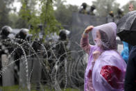 A woman stands at a barbed wire fence in front of a police line toward the Independence Palace, residence of the President Alexander Lukashenko, during Belarusian opposition supporters rally in Minsk, Belarus, Sunday, Sept. 6, 2020. Sunday's demonstration marked the beginning of the fifth week of daily protests calling for Belarusian President Alexander Lukashenko's resignation in the wake of allegedly manipulated elections. (AP Photo/TUT.by)