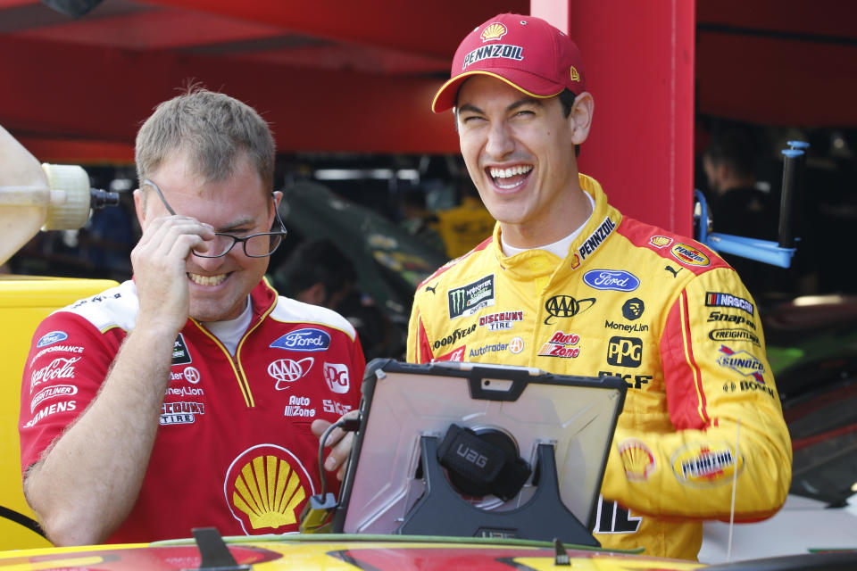 Joey Logano, right, shares a laugh with a crew member in the garage at Martinsville Speedway In Martinsville, Va., Saturday, Oct. 26, 2019. Elliott had an engine failure less than five minutes into the opening practice for the third round of NASCAR's playoffs. (AP Photo/Steve Helber)