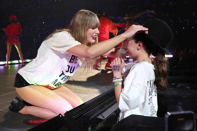 <p>Kevin Mazur/TAS24/Getty </p> Taylor Swift gifts a fan her hat while performing in Paris on May 10, 2024