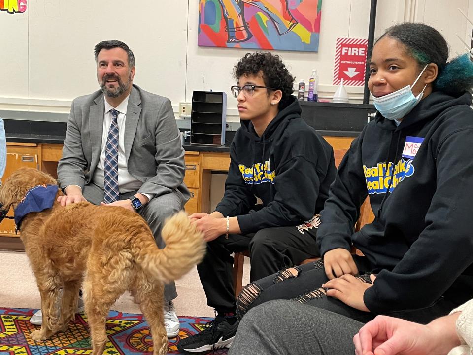 Rochester City School District Superintendent Carmine Peluso pets a therapy dog named Lily while listening to students Xavier Piner and Mari Curry at the Restorative HUB, the district's new restorative practices center at the Frederick Douglass campus.