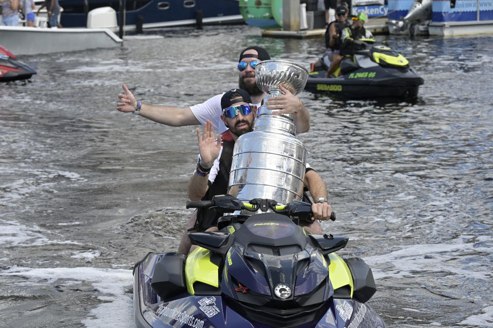 Tampa Bay Lightning left wing Alex Killorn and right wing Nikita Kucherov, rear, carry the Stanley Cup on a personal watercraft during the NHL hockey Stanley Cup champions' Boat Parade, Monday, July 12, 2021, in Tampa, Fla. (AP Photo/Phelan M. Ebenhack)