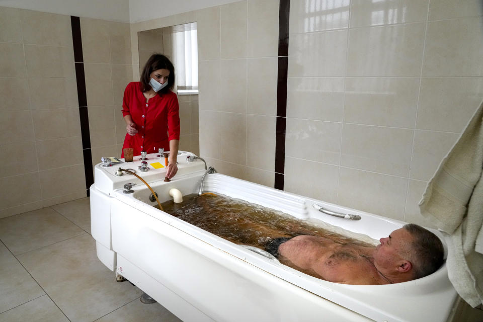 A visitor enjoys mineral water procedures in a spa sanatorium in Morshyn, Ukraine, Wednesday, Nov. 17, 2021. In Morshyn, a scenic town nestled at the Carparthian foothills in the Lviv region, 74% of 3,439 residents have been fully vaccinated. A small spa town in western Ukraine stands out in a country where just under a quarter of the population has received coronavirus vaccines. (AP Photo/Efrem Lukatsky)