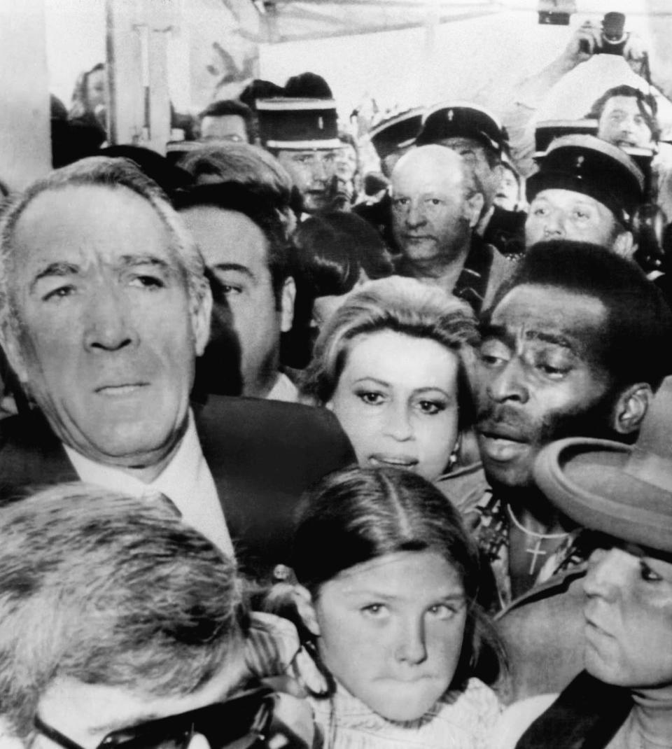 FILE - Actor Anthony Quinn, left, his wife Iolanda and Brazilian soccer star Pele, right, make their way through a crowd to attend the showing of the film Pele, directed by Francois Reichenbach and in which Pele stars, at the Cannes film festival in Cannes, France, May 18, 1977. Pelé, the Brazilian king of soccer who won a record three World Cups and became one of the most commanding sports figures of the last century, died in Sao Paulo on Thursday, Dec. 29, 2022. He was 82. (AP Photo/Jean Jacques Levy, File)