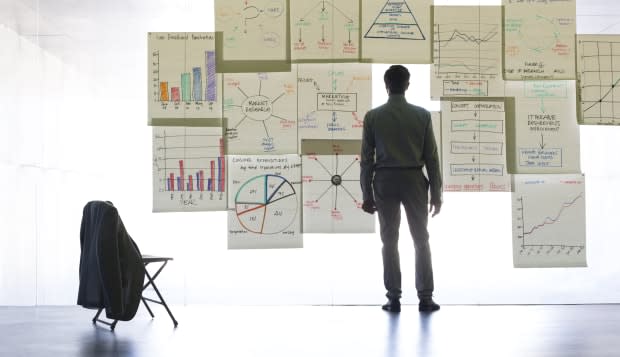 Businessman looking at graphs and charts on glass wall in office