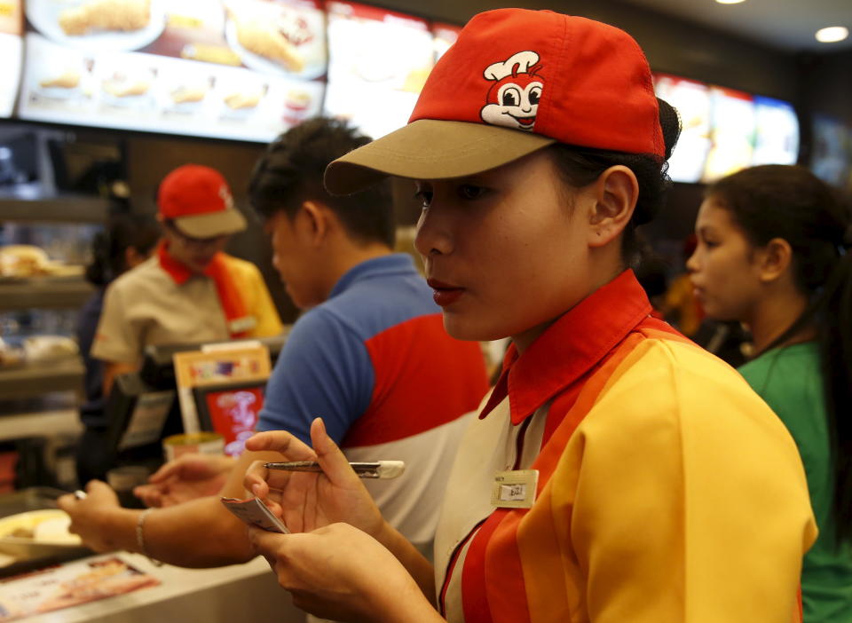 FILE PHOTO: A member of a Jollibee crew takes order from a customer inside a Jollibee franchise in Las Pinas, Metro Manila, February 28, 2016. REUTERS/Erik De Castro