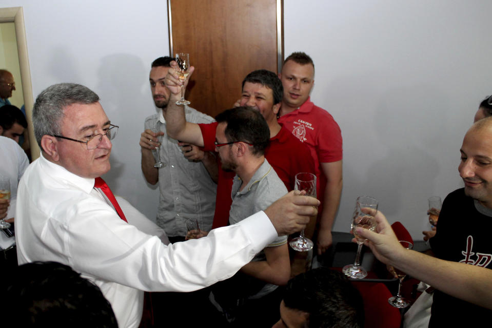 FILE - Albanian Football Federation President Armand Duka celebrates with journalists and other officials after being awarded victory over Serbia in the Euro qualifier by the top sports court, Tirana, Friday, July 10, 2015. A tournament co-hosting bid by Albania and Serbia is an unlikely project in European soccer and politics. The Balkan neighbors’ soccer federations have surprisingly teamed up to persuade UEFA to award them the men’s Under-21 European Championship. (AP Photo/Hektor Pustina, File)