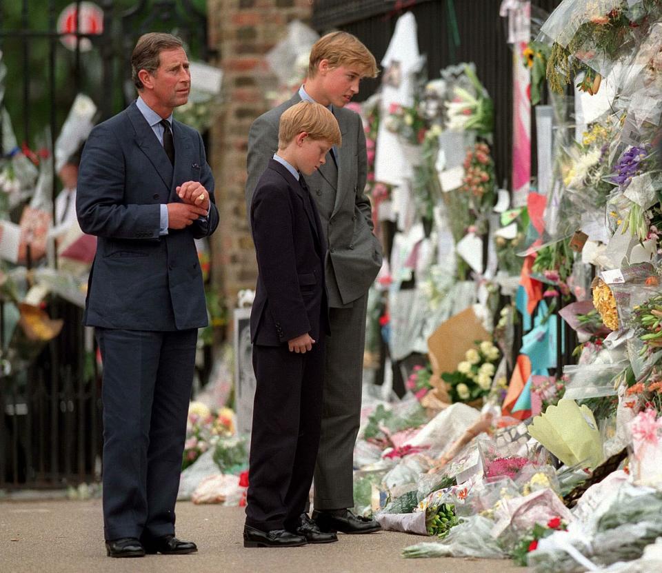 The Prince of Wales, Prince William and Prince Harry look at floral tributes to Diana, Princess of Wales outside Kensington Palace on September 5, 1997 in London, England