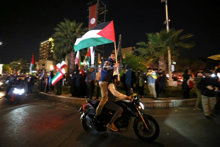 Des manifestants brandissent des drapeaux de la Palestine et de l'Iran, le 14 avril 2024 à Téhéran (ATTA KENARE)