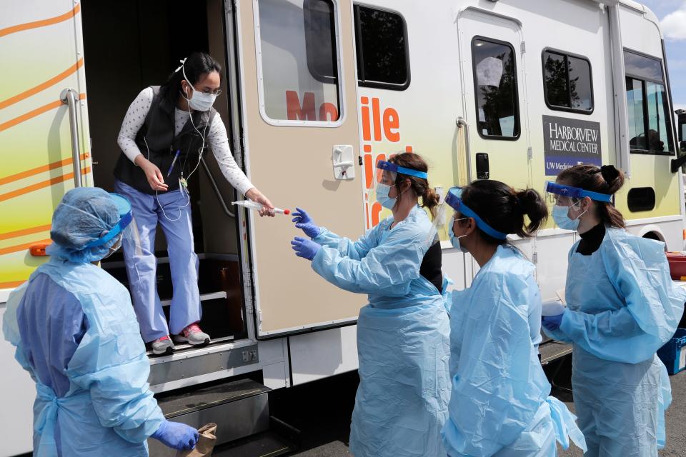 Medical assistants wait to be handed testing kits at a drive-up coronavirus testing site in Seattle.