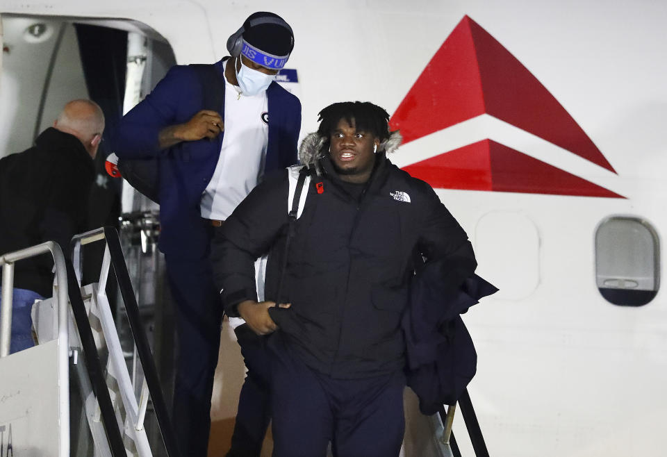Georgia defensive tackle Jordan Davis and teammates leave the plane after the team arrived at Indianapolis International Airport on Friday, Jan. 7, 2022, in Indianapolis. Georgia is scheduled to play Alabama in the College Football Playoff championship game Monday. (Curtis Compton/Atlanta Journal-Constitution via AP)