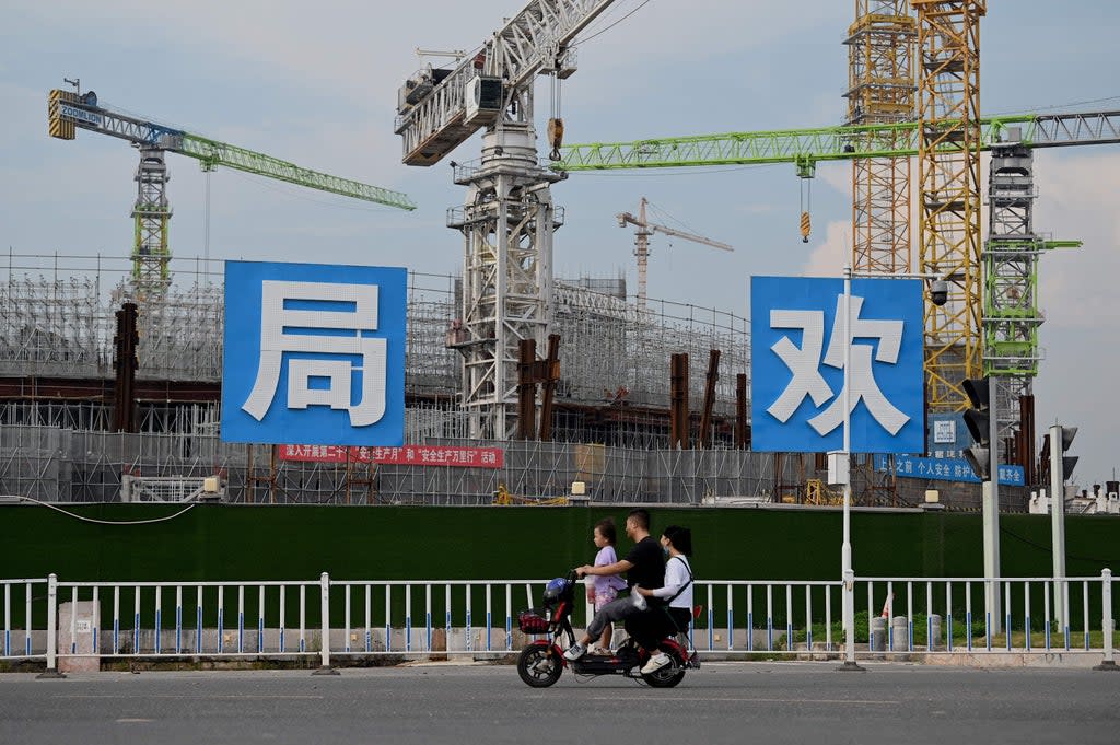 People commute in front of the under-construction Guangzhou Evergrande football stadium in Guangzhou, China’s southern Guangdong province  (AFP via Getty Images)