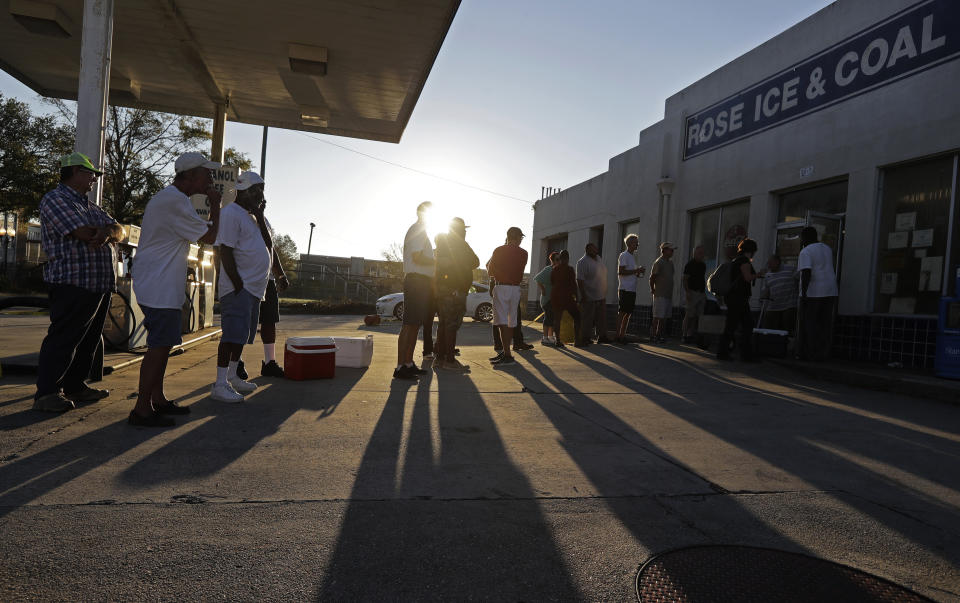 FILE - In this Sept. 19, 2018, file photo, people begin to form a line in the morning sun as they wait outside Rose Ice & Coal for it to open days after Hurricane Florence in Wilmington, N.C. Many in Wilmington woke up Wednesday suddenly very tired. The days-long scavenger hunt for gas and ice was over as stores opened and relief agencies were able to roll into the city. (AP Photo/Chuck Burton, File)