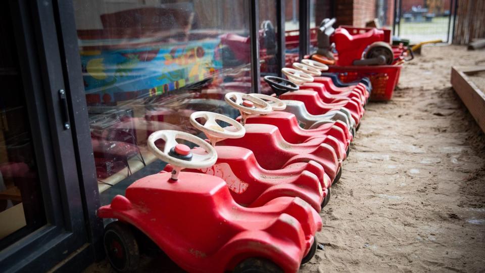 Mehrere Bobbycars stehen auf dem Spielplatz eines Kindergartens.