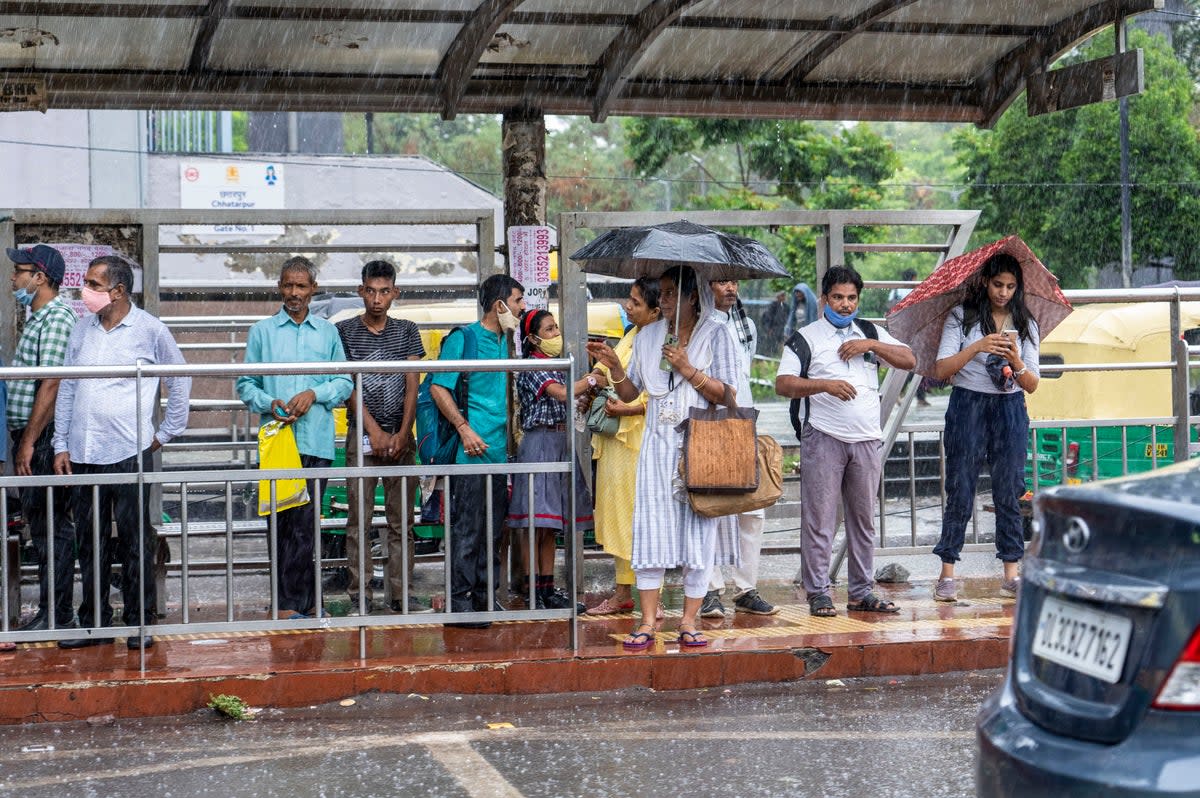 People wait for public transport as it rains in New Delhi  (AP)