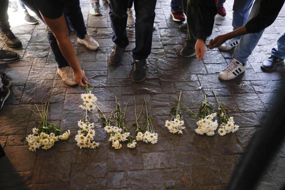 Gente deja flores durante una protesta contra el incendio en un centro de detención de migrantes que dejó más de tres docenas de muertos, a las afueras de la embajada mexicana en Caracas, Venezuela, el miércoles 29 de marzo de 2023. Las autoridades de Migración identificaron a nacionales de Guatemala, Honduras, El Salvador, Venezuela, Colombia y Ecuador entre los muertos y los heridos. (AP Foto/Matías Delacroix)