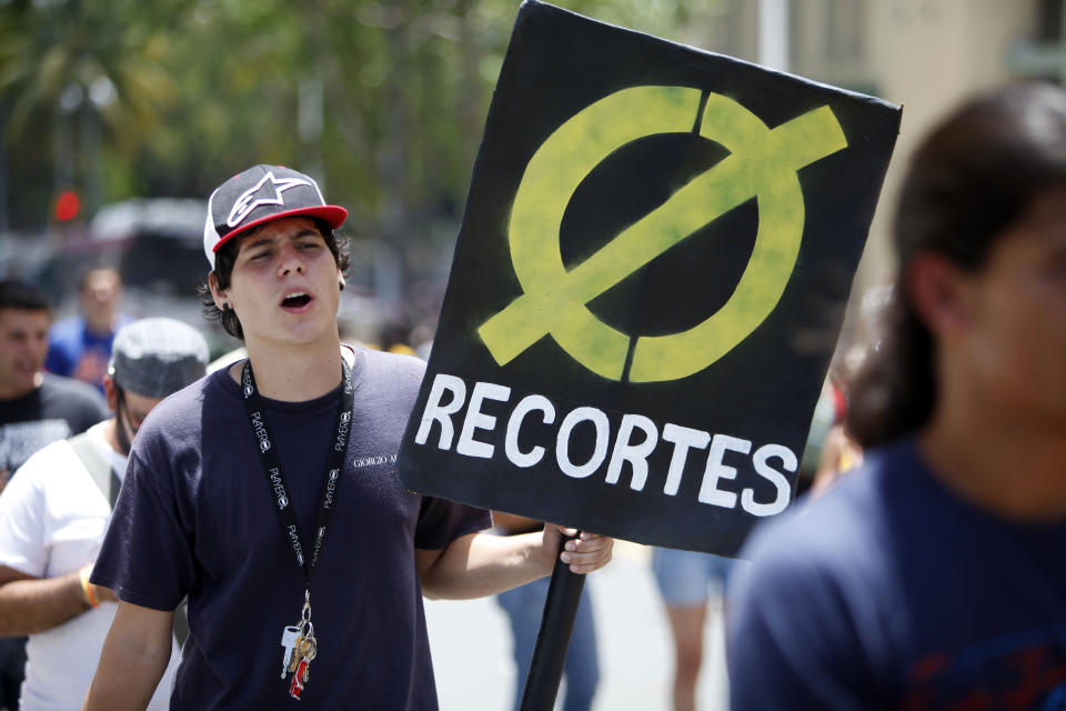 A student holds up a sign that reads in Spanish "Zero cuts" during a protest against a tuition increase outside the University of Puerto Rico in San Juan, Puerto Rico, Wednesday, April 23, 2014. The 24-hour protest was called even though officials at the university have extended a one year moratorium on the four percent increase. (AP Photo/Ricardo Arduengo)