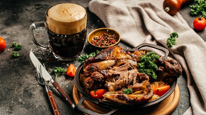 A glass of beer next to a tender shredded meat dish