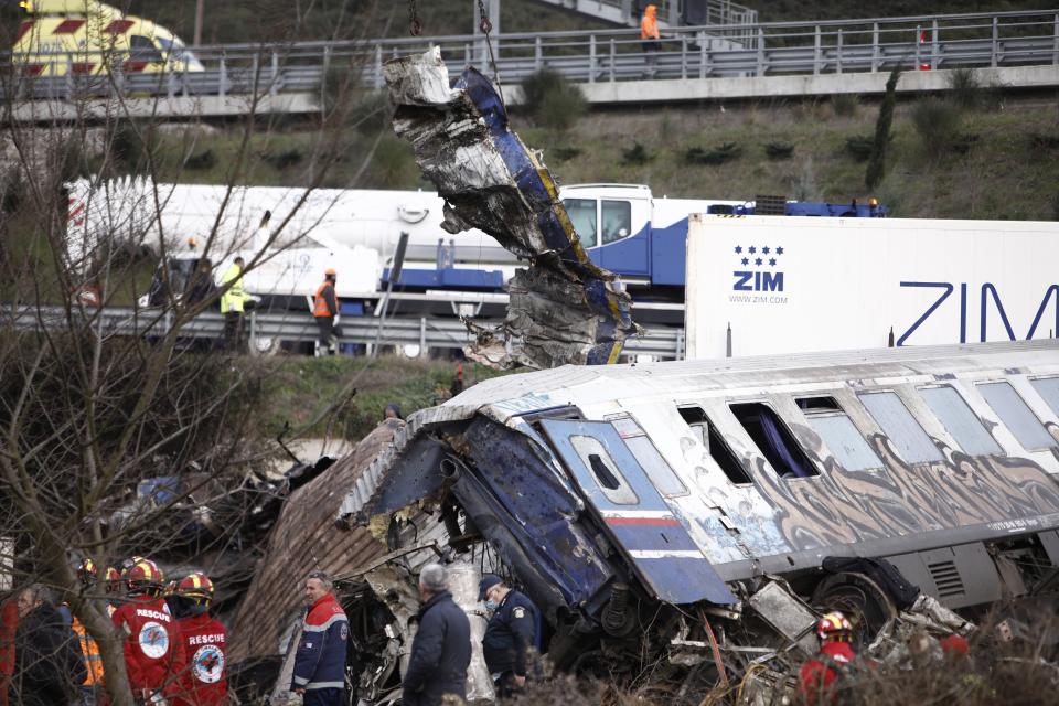 Rescuers stand near debris of trains after a collision in Tempe, about 376 kilometres (235 miles) north of Athens, near Larissa city, Greece, Wednesday, March 1, 2023. Rescuers searched Wednesday through the burned-out wreckage of two trains that slammed into each other in northern Greece, killing and injured dozens of passengers. (AP Photo/Giannis Papanikos)