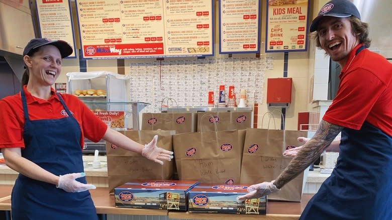 two smiling servers making sandwhiches 