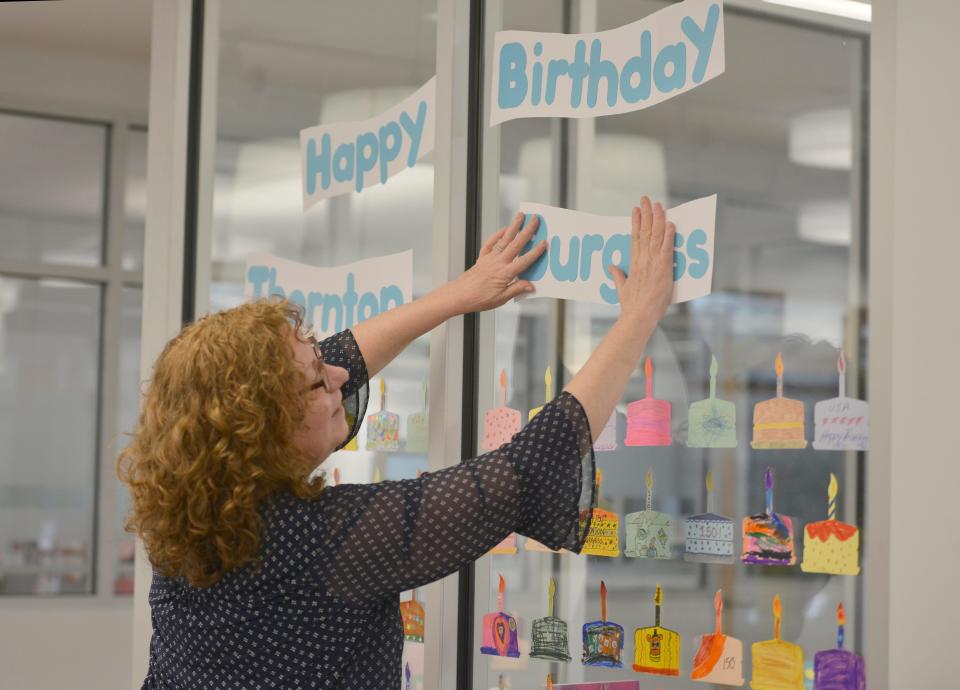 Sandwich children and youth services librarian Pam Carmichael hangs a window display celebrating Thornton Burgess' birthday. They are trying to get library users to decorate 150 of these paper cakes to hang in the window of the children's section of the library. Sandwich is celebrating the 150th birthday year of renowned author and conservationist Thornton Burgess, a Sandwich native.