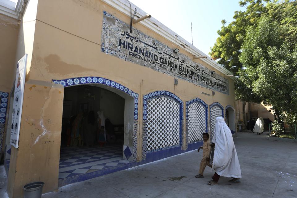 A woman with a child arrive in historical Hira Nand Ganga Bhai hospital, in Shikarpur, Pakistan, Wednesday, Oct. 26, 2022. The landscape of Pakistan, and Sindh in particular, retains their imprint. It has temples, although their numbers have plummeted, businesses, education and healthcare institutions, many established before the country was created in 1947. These places are part of Pakistan's heritage, even as Hindus are forced into the shadows. (AP Photo/Fareed Khan)