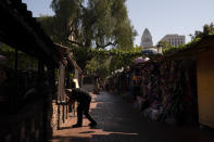 Peter Alamillo, one of managers at El Paseo Inn Mexican restaurant on Olvera Street, pulls down a blind for customers in the patio area of the restaurant in Los Angeles, Friday, June 4, 2021. As Latinos in California have experienced disproportionately worse outcomes from COVID-19, so too has Olvera Street. The shops lining the narrow brick walkway rely heavily on participants at monthly cultural celebrations, downtown office workers dining out, school field trips and Dodger baseball fans loading up on Mexican food before or after games. But the coronavirus killed tourism, kept office workers and pupils at home, cancelled events and kept fans from sporting events. (AP Photo/Jae C. Hong)