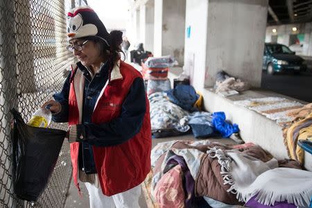 Blanca Rodriguez, 46, cleans up her sleeping area under an overpass in Chicago, December 4, 2014. Rodriguez has been living under the overpass for 3 months. REUTERS/Andrew Nelles